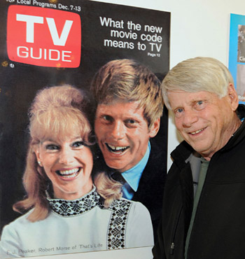 Robert Morse poses next to a 1968 cover of <i>TV Guide</i> featuring himself and <i>That's Life</i> co-star E.J. Peaker. (Photo courtesy of the Paley Center for Media.)